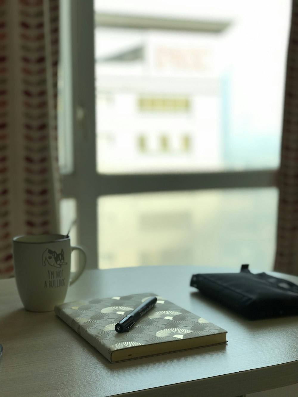 black remote control beside white ceramic mug on white table