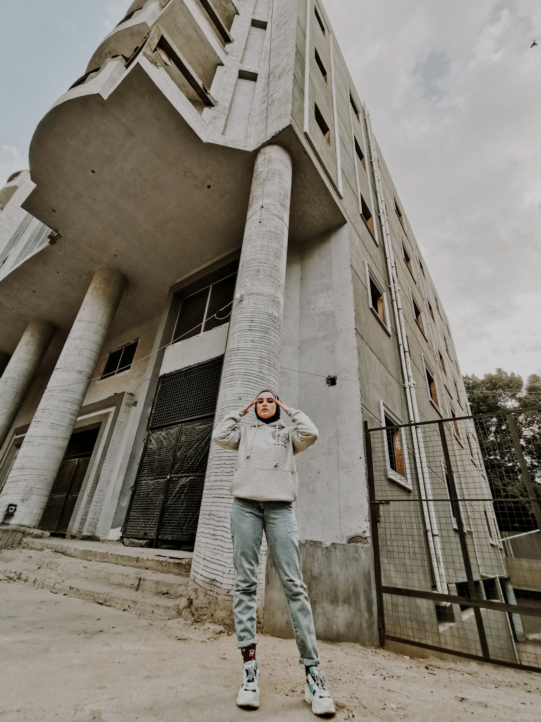 man in white t-shirt and blue denim jeans standing in front of beige concrete building