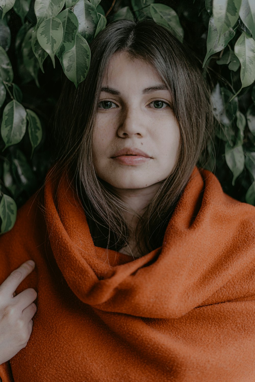woman in orange scarf standing beside green plant