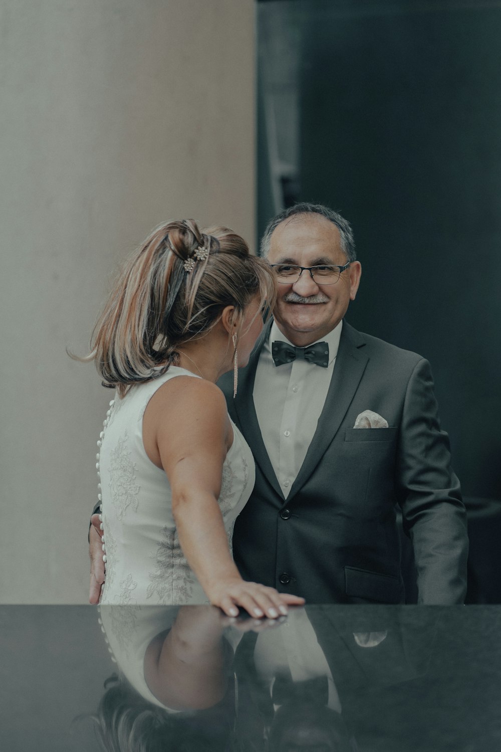 man in black suit jacket kissing woman in white sleeveless dress