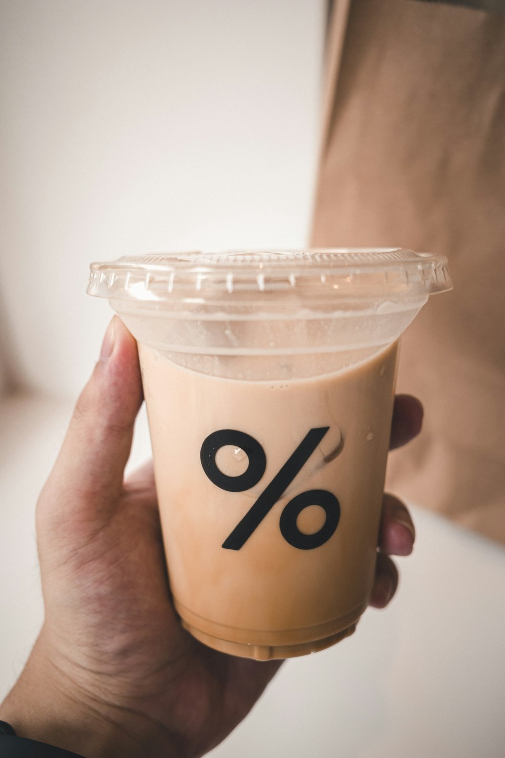 person holding white plastic cup with brown liquid