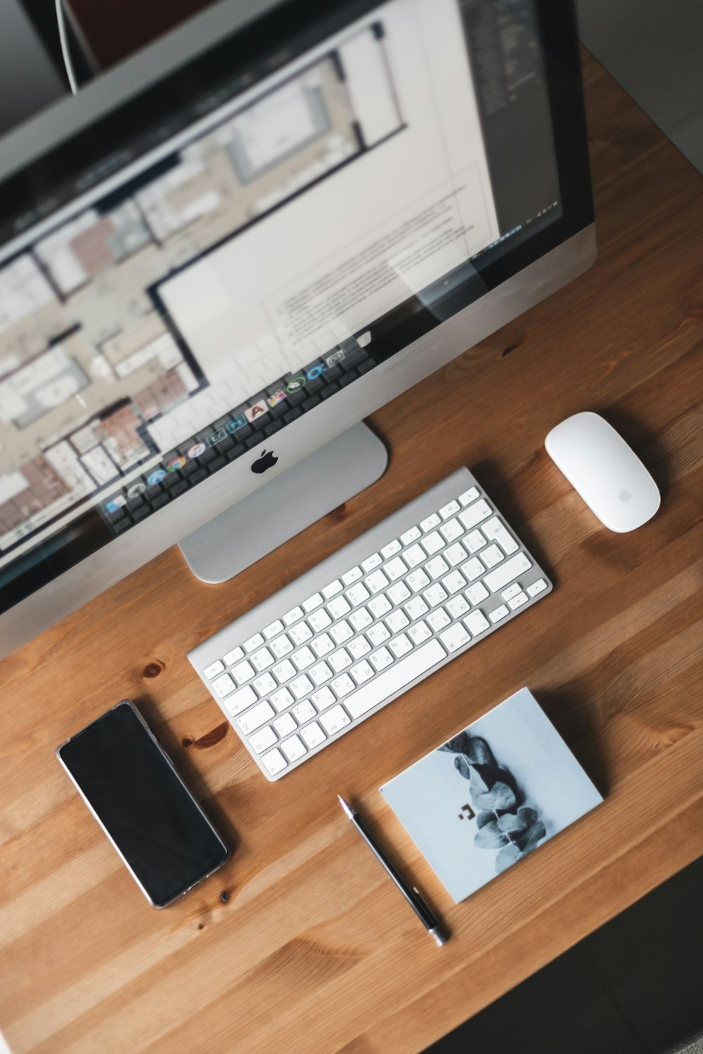 iMac plateado junto al teclado mágico de Apple y el mouse mágico sobre un escritorio de madera marrón