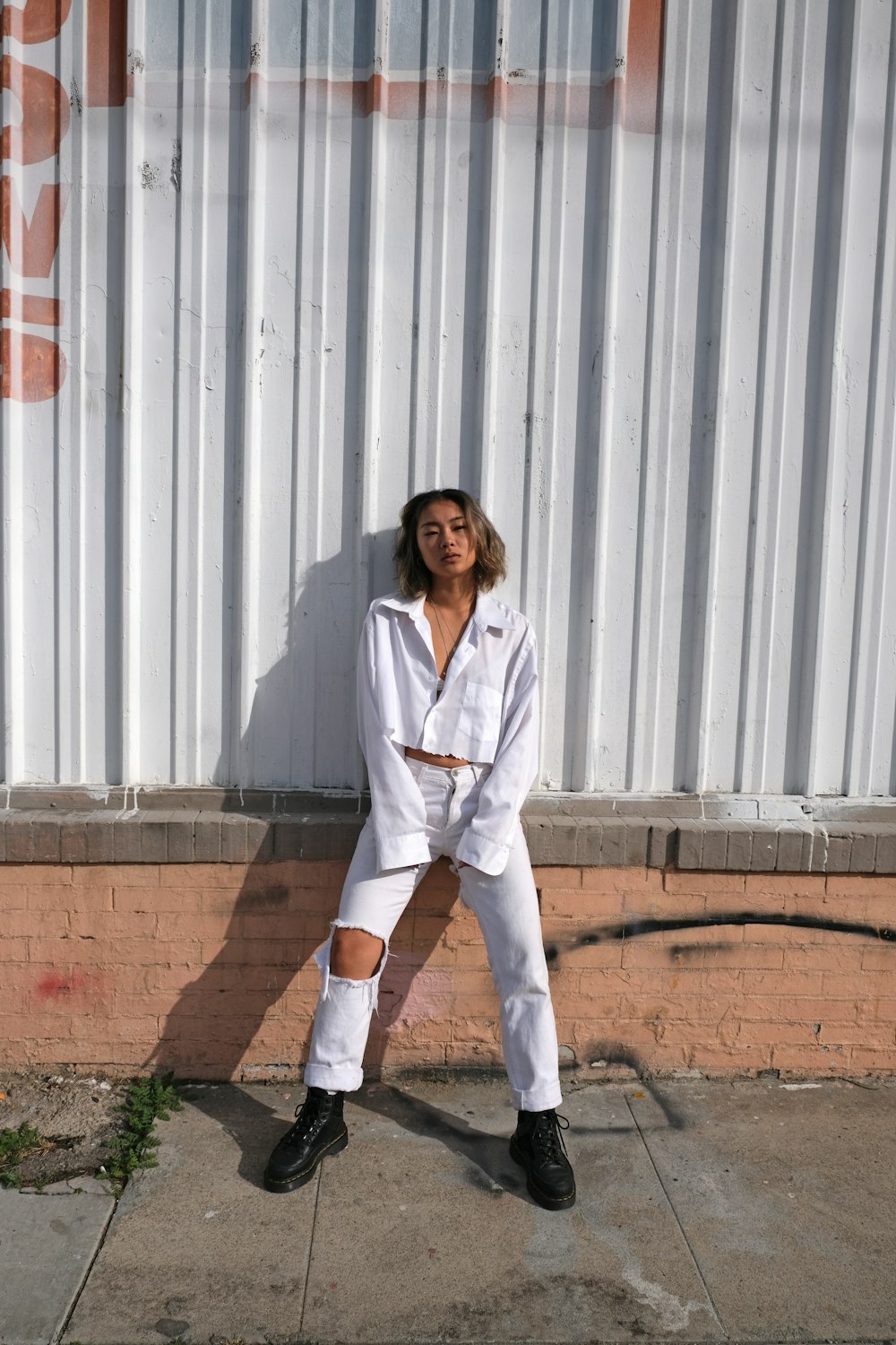 Mujer en blazer blanco y pantalones blancos de pie sobre suelo marrón