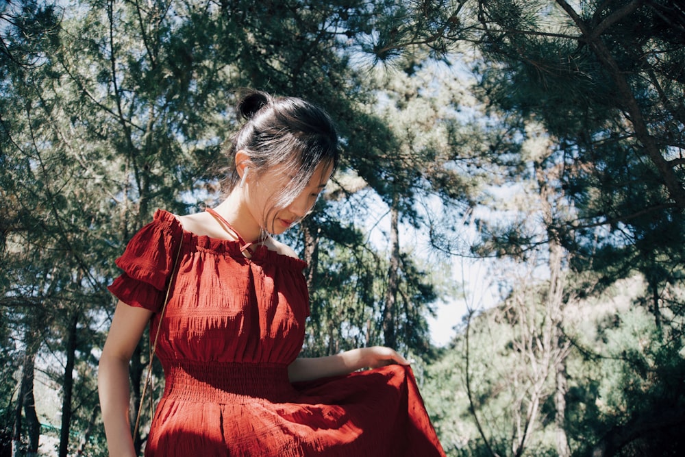 woman in red dress sitting on brown tree during daytime