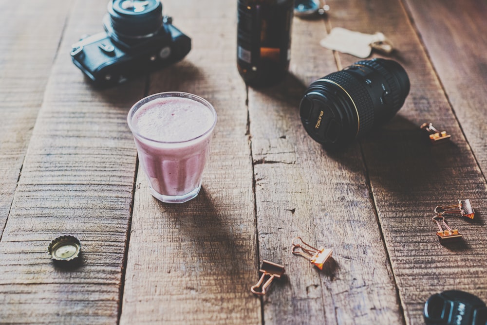 black dslr camera beside pink drinking glass