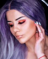 A smiling person applying Violetaura lotion to their earlobes, surrounded by purple hues.