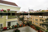 Balcony overlooking bustling city streets with tropical plants.