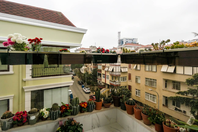 Balcony overlooking bustling city streets with tropical plants.