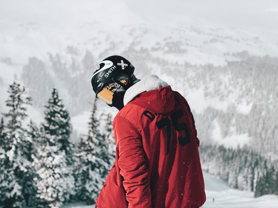 person in red jacket and black helmet standing on snow covered ground during daytime