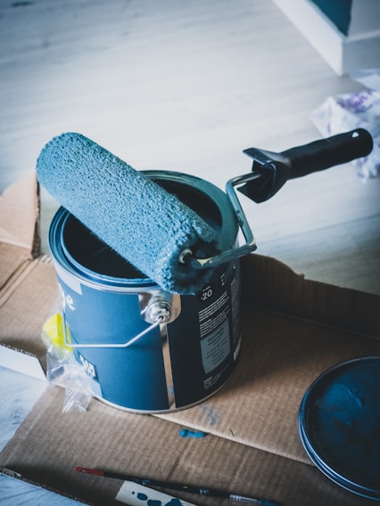 pot de peinture bleue avec rouleau posé dessus