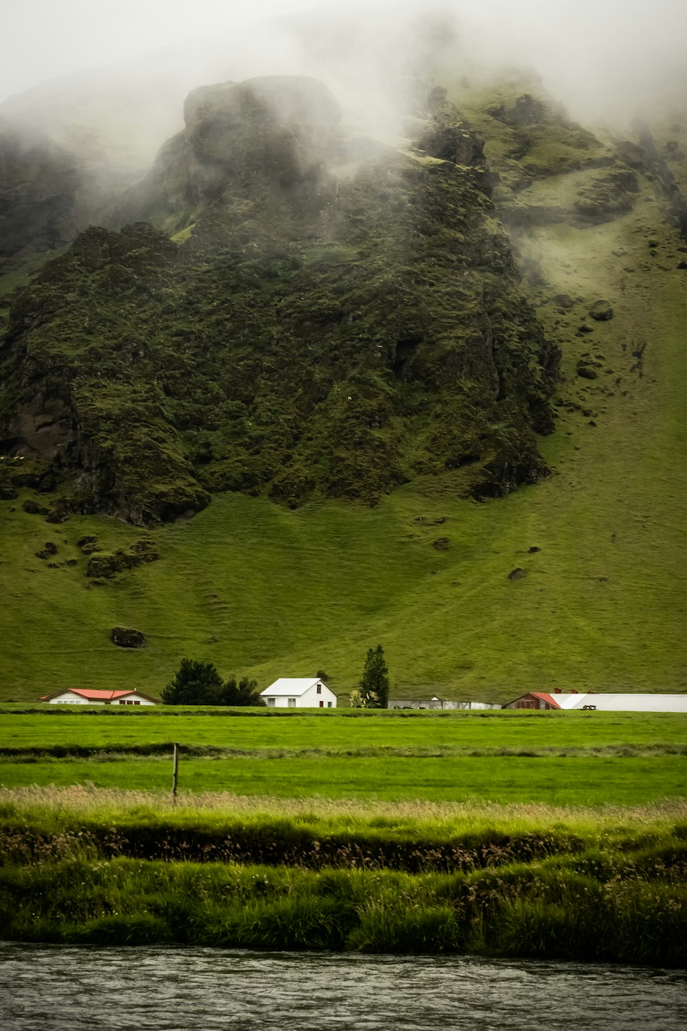 white and red house on green grass field near mountain during daytime