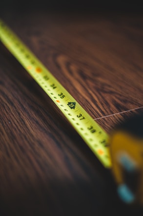 yellow measuring tape on brown wooden table