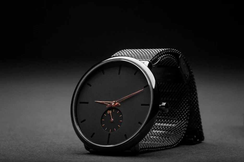 A sleek, modern black watch with subtle gold accents displayed on a dark minimalist background.