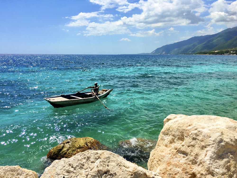 man in red shirt riding on boat on sea during daytime