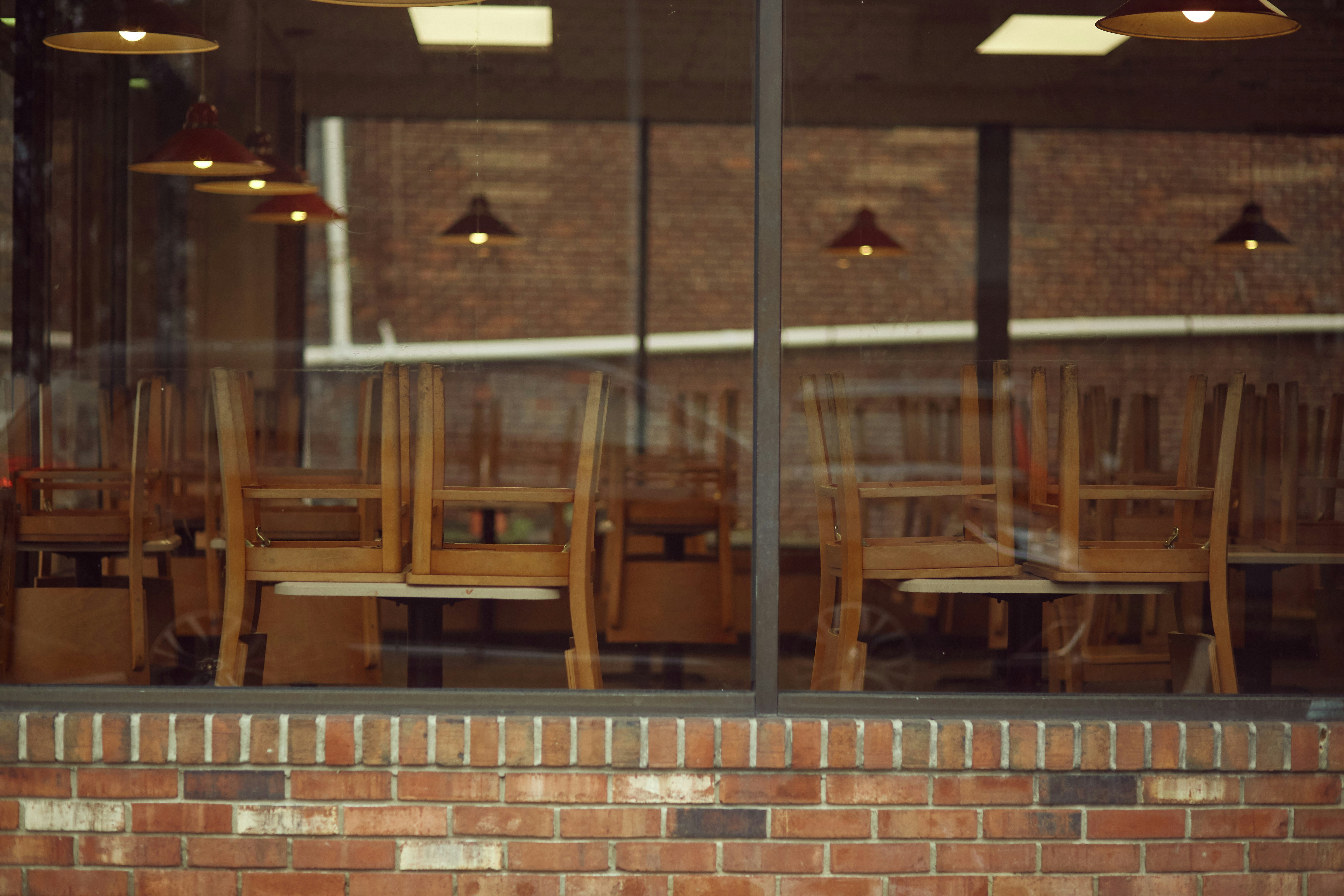 Empty restaurant chairs and tables seen through window.
