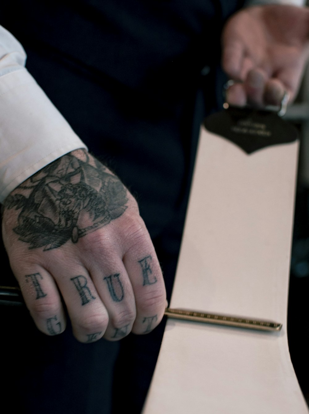 person with tattoo on left hand holding brown and black book