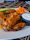 Plate of crispy boneless wings with a side of dipping sauce and fresh celery sticks.