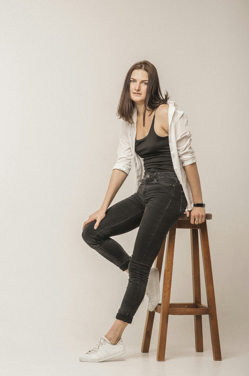 woman in white long sleeve shirt and black denim jeans sitting on brown wooden chair