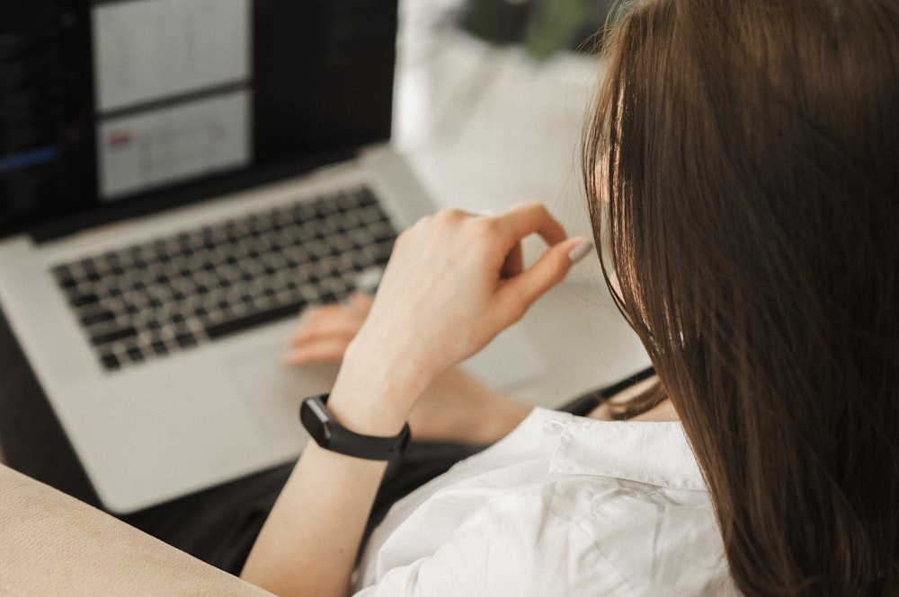 woman in white shirt using macbook pro