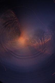 A swirling canvas of deep blues and purples depicting a misty forest where shadowy figures emerge from the fog.