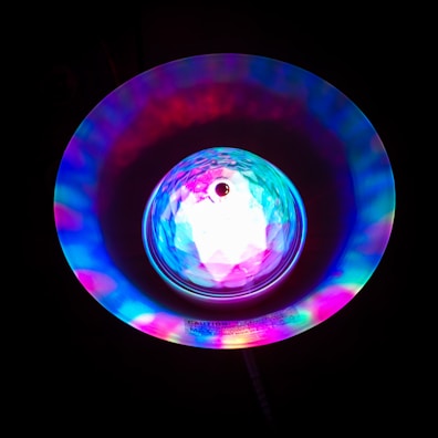 A vibrant, colorful light display featuring a central crystal-like structure surrounded by a radiant halo of multicolored lights, creating a mesmerizing effect against a dark background.