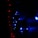 A string of bright blue LED lights arranged in a pattern, with smaller red lights forming a line to the left. The scene is dark, emphasizing the vivid glow of the lights against the shadowy background.