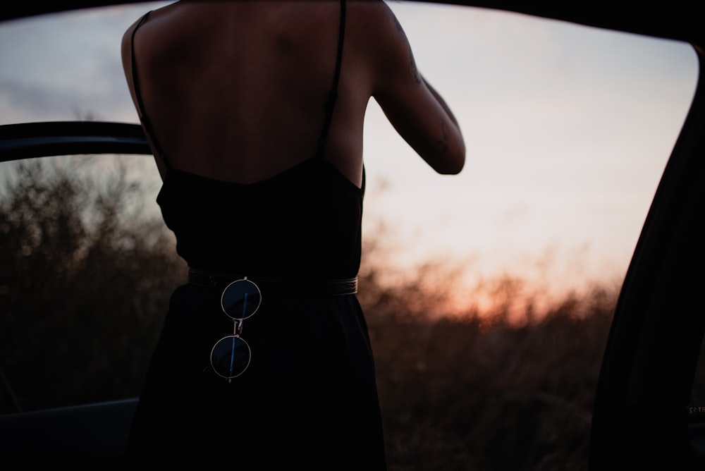 woman in black spaghetti strap dress holding her hair