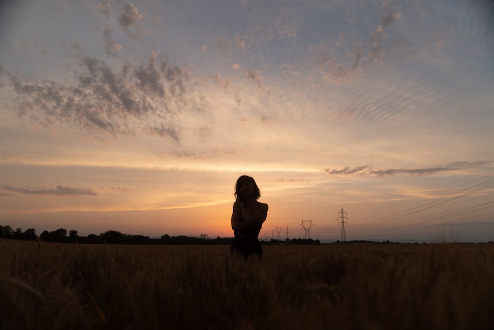 silhouette of person standing on grass field during sunset