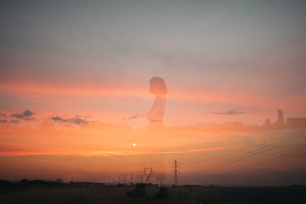 silhouette of person standing on hill during sunset