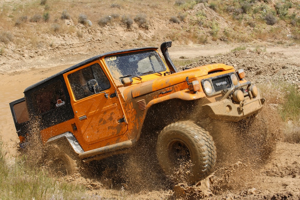 orangefarbener SUV auf braunem Sand tagsüber