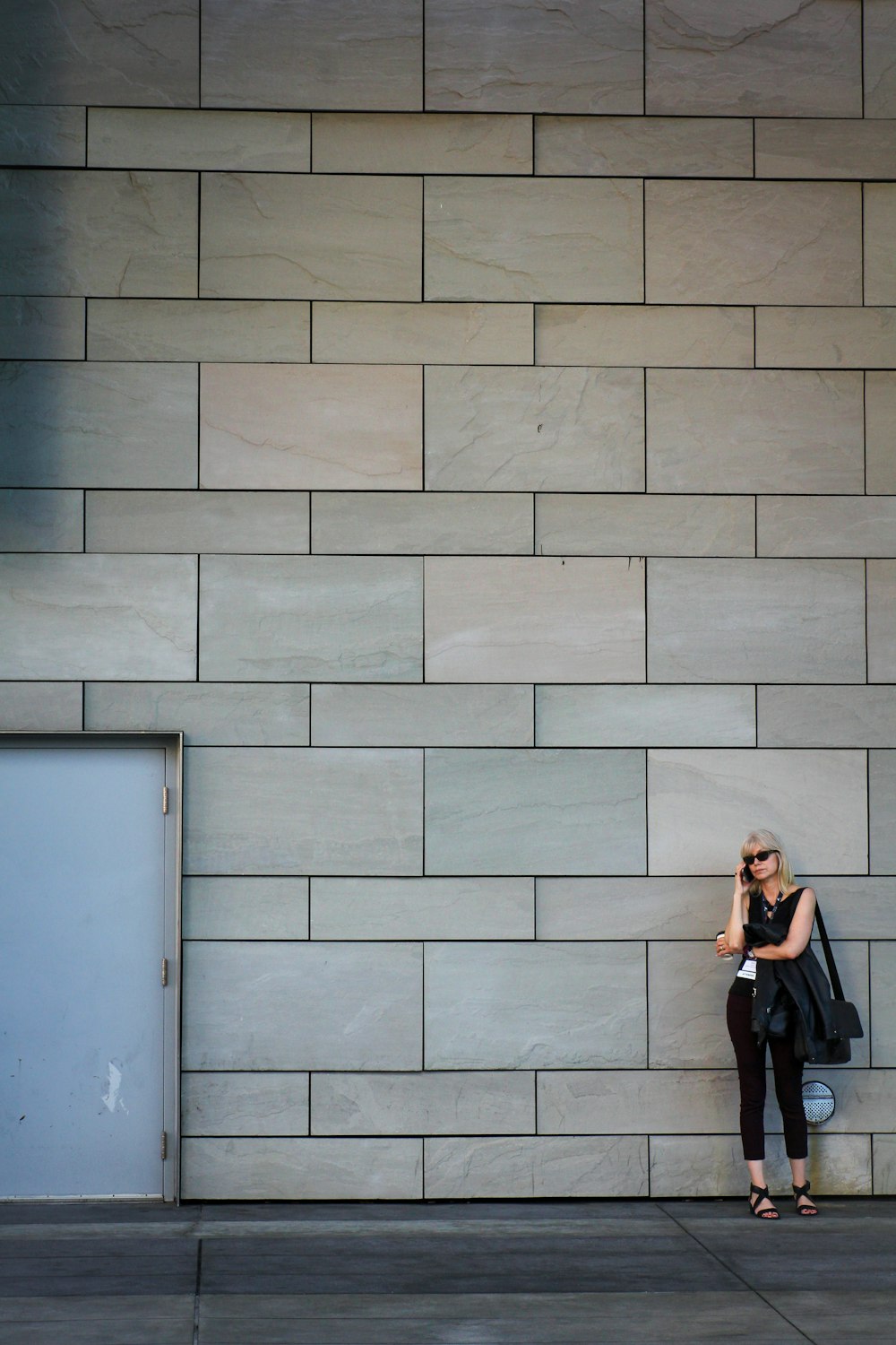 woman in black long sleeve shirt and black pants standing beside blue wall