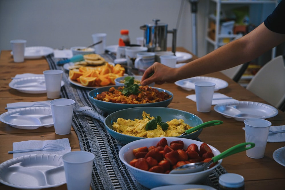 person holding green plastic bowl with food