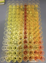 A symmetrical arrangement of test tubes filled with liquids, transitioning from bright yellow to deep orange.