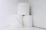 Three rolls of toilet paper are stacked in a minimalist arrangement against a plain white background.