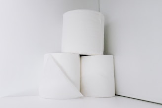Three rolls of toilet paper are stacked in a minimalist arrangement against a plain white background.