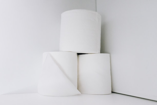 Close-up of a neatly stacked bundle of soft, white toilet paper rolls with a subtle embossed pattern.