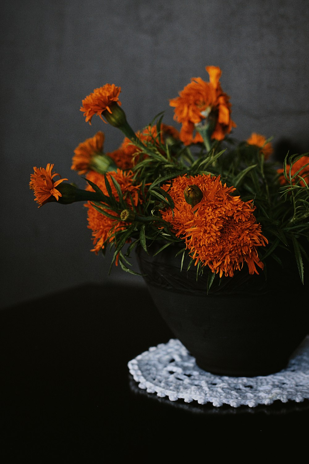 orange and yellow flowers in black ceramic vase