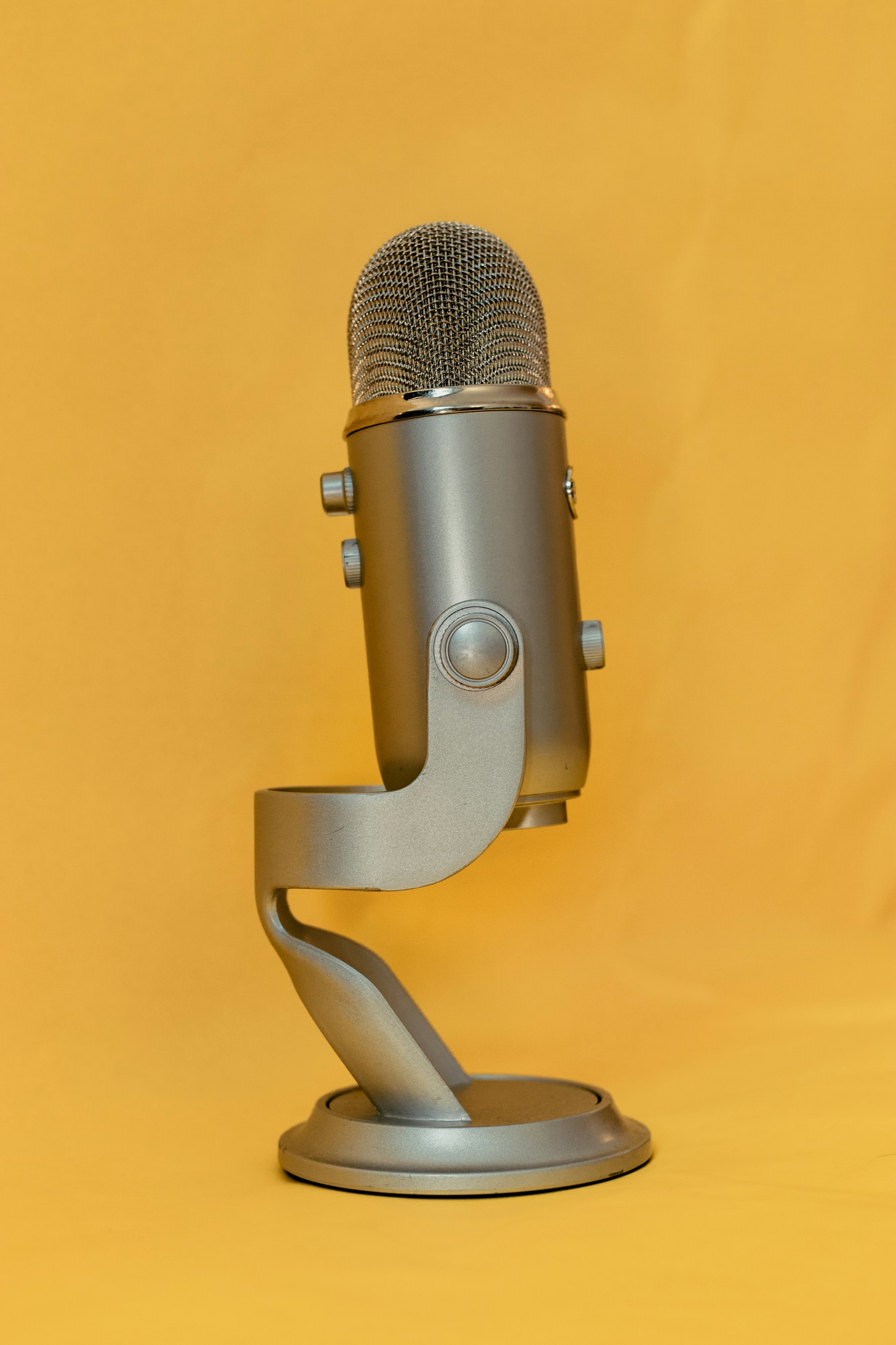 A microphone on its stand with a yellow background