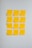 Twelve yellow sticky notes are arranged in a grid on a light gray wall. Each note contains a part of a message written in black ink, which together form a religious or inspirational quote.