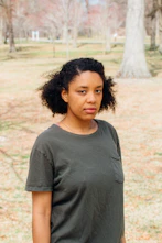 woman in gray crew neck t-shirt standing on brown field during daytime