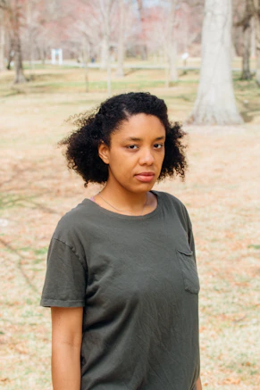 woman in gray crew neck t-shirt standing on brown field during daytime
