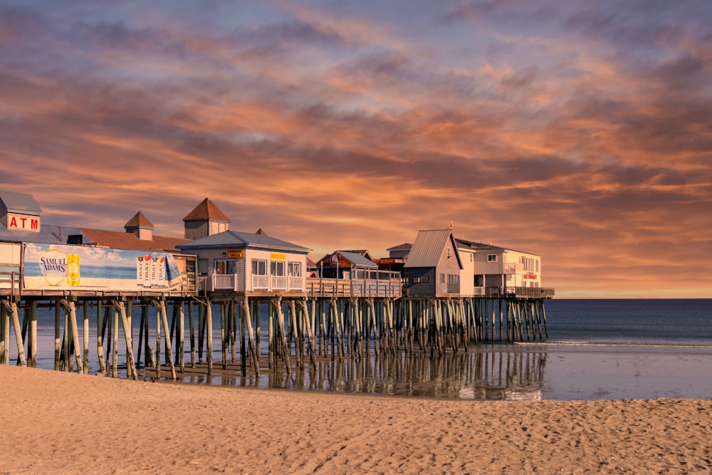 white and brown wooden house on sea shore during sunset