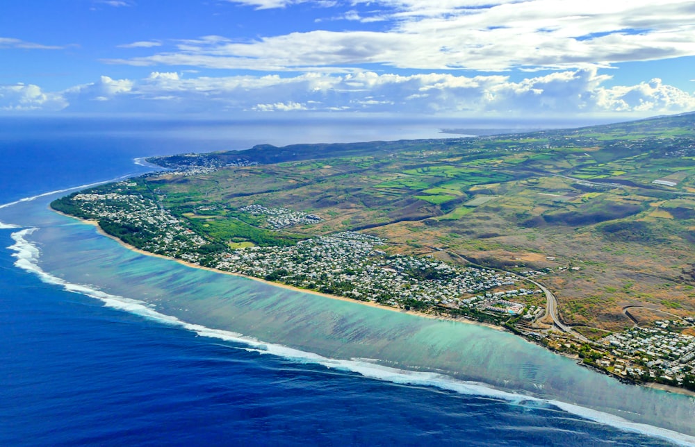 aerial view of green and brown field beside body of water during daytime