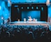 people standing on stage with lights turned on during nighttime