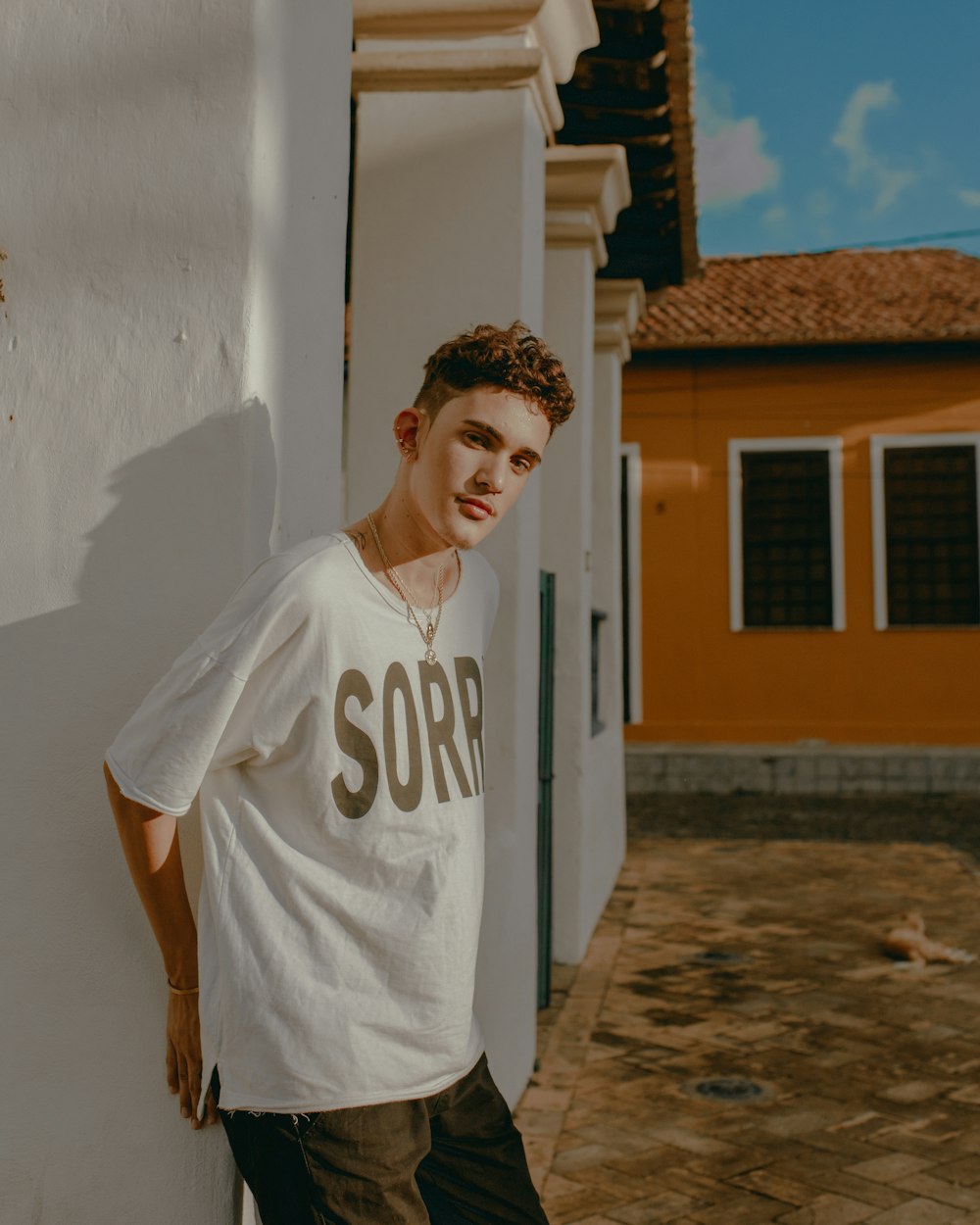 man in white and blue crew neck t-shirt standing near white wall during daytime