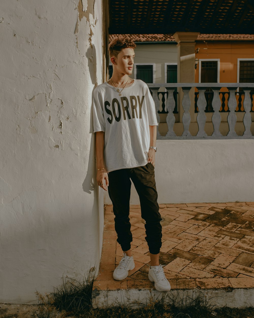 man in white and black adidas crew neck t-shirt and black pants standing beside white