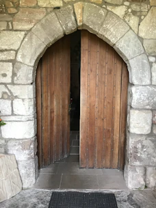 An ancient wooden lodge door partially open welcoming members.