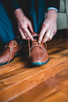 Worker lacing up a pair of brown leather safety shoes before starting a day outdoors.