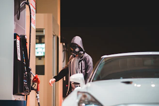 Technician carefully cleaning a fuel pump at a gas station with protective gear.