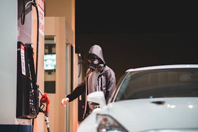 Technician carefully cleaning a fuel pump at a gas station with protective gear.